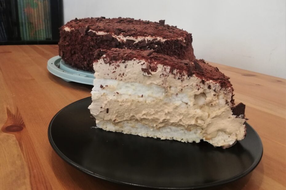 Ein Stück Merveilleux mit restlichem Kuchen im Hintergrund